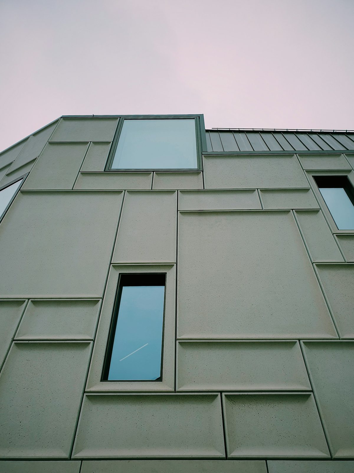 Gevel met groene gevelpanelen en een verticaal raam